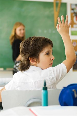 Boy raising hand in class, looking over shoulder Foto de stock - Sin royalties Premium, Código: 632-03193670