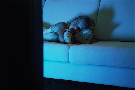 Girl lying on sofa with teddy bear, watching TV Stock Photo - Premium Royalty-Free, Code: 632-03424701