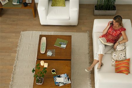 Woman relaxing on sofa with book on lap, talking on cell phone Foto de stock - Sin royalties Premium, Código: 632-03500800