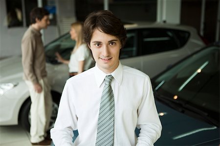 simsearch:632-03083042,k - Car salesman in car dealership showroom, potential buyers in background Stock Photo - Premium Royalty-Free, Code: 632-03500906