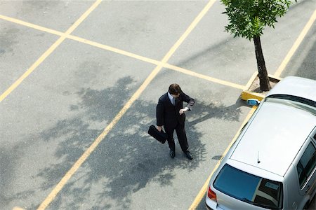 parking lot - Businessman checking time as he walks to parked car Stock Photo - Premium Royalty-Free, Code: 632-03500939