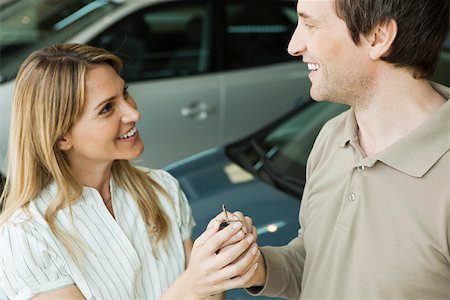Couple in car dealership showroom with key to new car Stock Photo - Premium Royalty-Free, Code: 632-03500941