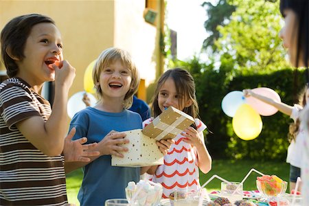 Boy opening gift and smiling with pleasure at birthday party Stock Photo - Premium Royalty-Free, Code: 632-03500972