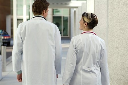 picture of people walking and chatting - Doctors chatting and walking together along hospital corridor, rear view Stock Photo - Premium Royalty-Free, Code: 632-03516477