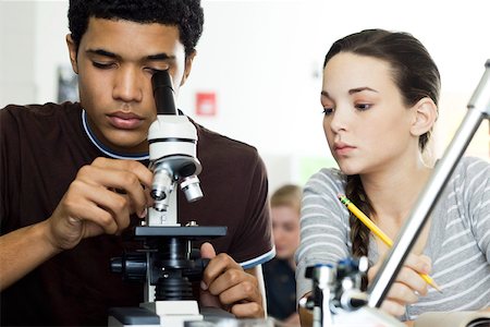 Student looking through microscope in science class Stock Photo - Premium Royalty-Free, Code: 632-03516581