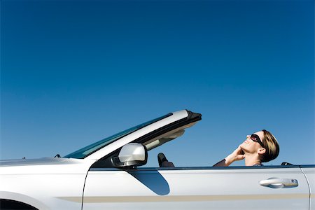 Woman talking on cell phone while driving convertible Stock Photo - Premium Royalty-Free, Code: 632-03516875
