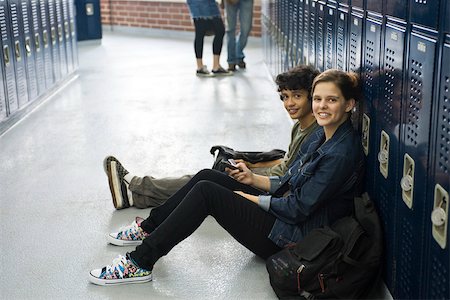 High school student sitting on floor with friend by lockers in school corridor Stock Photo - Premium Royalty-Free, Code: 632-03630160