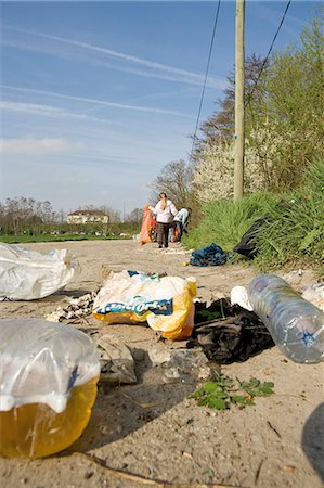 dirty environment - Trash dumped on dirt road, volunteers in background cleaning up Stock Photo - Premium Royalty-Free, Code: 632-03651658