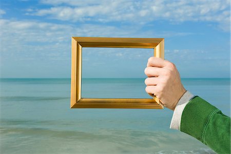 Person holding picture frame in front of ocean Stock Photo - Premium Royalty-Free, Code: 632-03651822