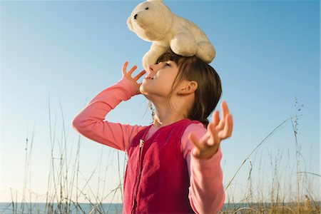 Young girl outdoors balancing stuffed polar bear on head Stock Photo - Premium Royalty-Free, Code: 632-03754506