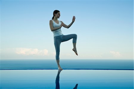 Woman practicing Tai Chi Chuan on edge of infinity pool Stock Photo - Premium Royalty-Free, Code: 632-03779592