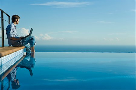 pool sky - Man sitting at edge of infinity pool with laptop computer, looking at view Stock Photo - Premium Royalty-Free, Code: 632-03779611