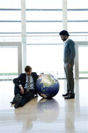 Businessmen contemplating ball in lobby Stock Photo - Premium Royalty-Free, Code: 632-03848136