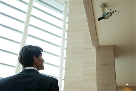 simsearch:632-03403433,k - Businessman looking up at security camera Stock Photo - Premium Royalty-Free, Code: 632-03848148