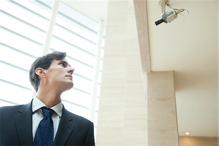 simsearch:632-03403433,k - Businessman looking up at security camera Stock Photo - Premium Royalty-Free, Code: 632-03848154