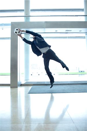 Businessman catching soccer ball in lobby Stock Photo - Premium Royalty-Free, Code: 632-03848152