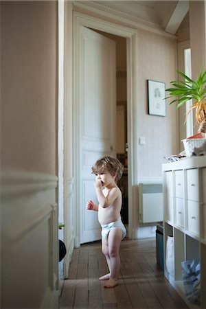 preschooler in diapers - Toddler boy standing in hall, eating a snack Stock Photo - Premium Royalty-Free, Code: 632-03848304