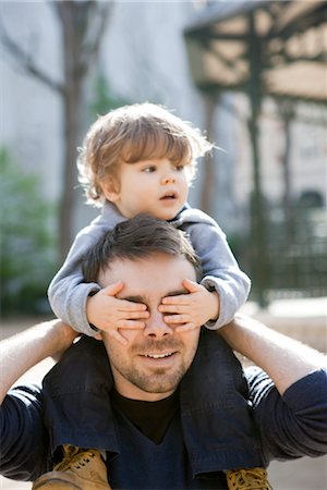simsearch:632-03848361,k - Father carrying toddler son on his shoulders, son covering father's eyes with his hands Stock Photo - Premium Royalty-Free, Code: 632-03848303