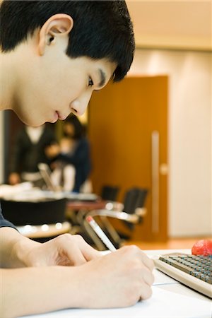 Young man writing at desk Stock Photo - Premium Royalty-Free, Code: 632-03898394