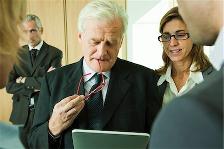 Mature executive examining information on digital tablet with colleagues Stock Photo - Premium Royalty-Free, Code: 632-03898431