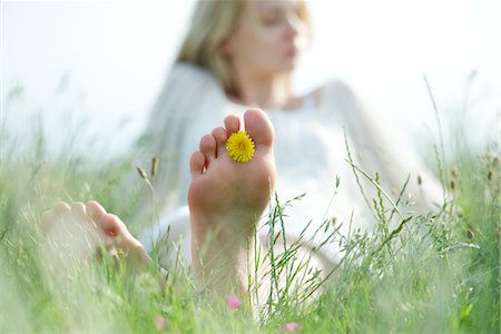 sole of foot - Barefoot young woman sitting in grass with dandelion flower between toes, cropped Stock Photo - Premium Royalty-Free, Code: 633-05401339