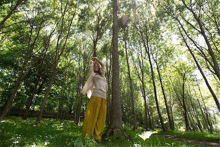 Young woman standing in forest with arms raised in air Stock Photo - Premium Royalty-Free, Code: 633-05401408