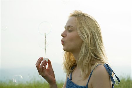 summer light - Young woman blowing bubbles with bubble wand Foto de stock - Sin royalties Premium, Código: 633-05401474