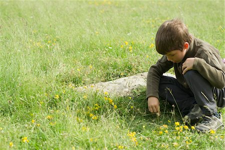 simsearch:633-05401710,k - Boy crouching in grass, looking at something on the ground Stock Photo - Premium Royalty-Free, Code: 633-05401634