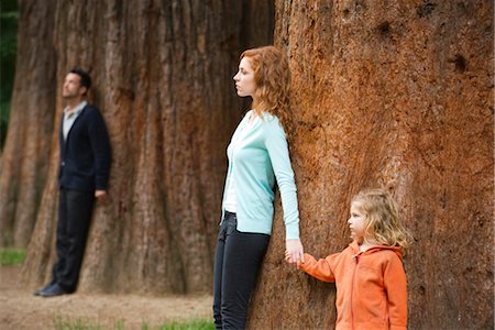 separate - Mother and daughter leaning against tree, father standing separate in background Stock Photo - Premium Royalty-Free, Code: 633-05401845