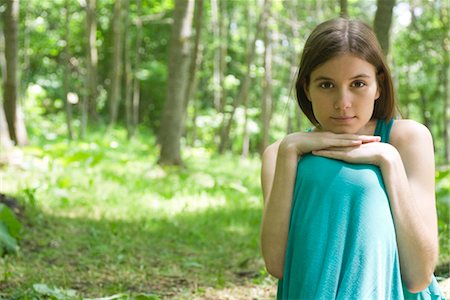 Young woman sitting in woods with chin resting on knees, portrait Stock Photo - Premium Royalty-Free, Code: 633-05401978