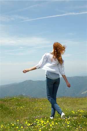 Woman walking through meadow with arms outstretched Stock Photo - Premium Royalty-Free, Code: 633-05402017