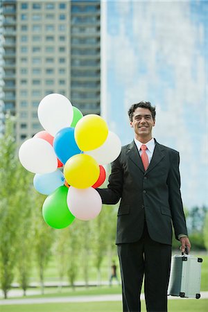 simsearch:632-05604036,k - Smiling businessman holding bunch of balloons Stock Photo - Premium Royalty-Free, Code: 633-06322392