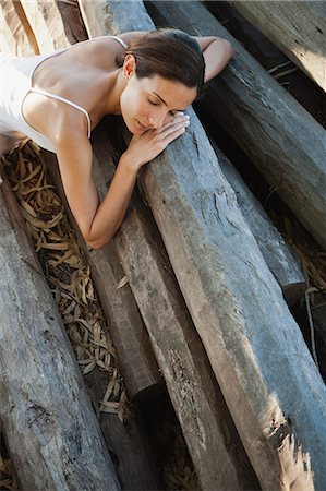 simsearch:633-06354677,k - Woman reclining on pile of logs Stock Photo - Premium Royalty-Free, Code: 633-06354643