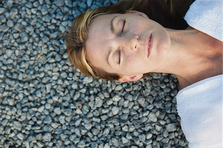 simsearch:633-06354677,k - Mid-adult woman lying on gravel with eyes closed, cropped Stock Photo - Premium Royalty-Free, Code: 633-06354815