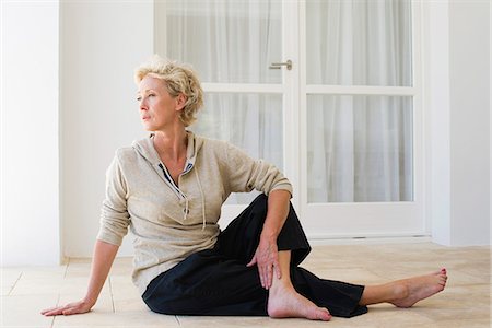 Mature woman sitting on floor doing spinal twist Stock Photo - Premium Royalty-Free, Code: 633-06354945