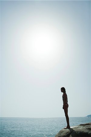 Girl in bikini standing on edge of cliff looking at ocean Stock Photo - Premium Royalty-Free, Code: 633-06355040