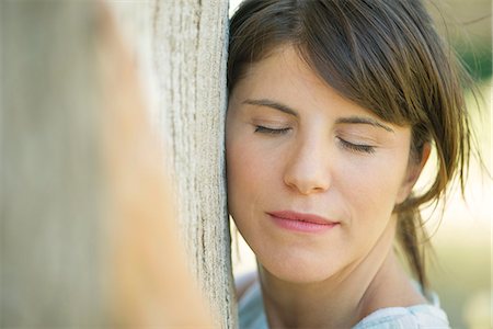 Woman leaning against tree trunk with eyes closed, portrait Foto de stock - Sin royalties Premium, Código: 633-08150770