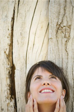 simsearch:632-05760692,k - Woman leaning against tree trunk, looking up and smiling Stock Photo - Premium Royalty-Free, Code: 633-08150982