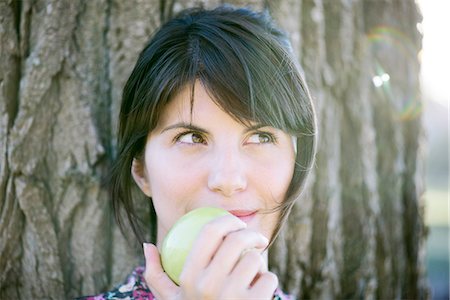 Woman eating apple, looking up thoughtfully Stock Photo - Premium Royalty-Free, Code: 633-08482094