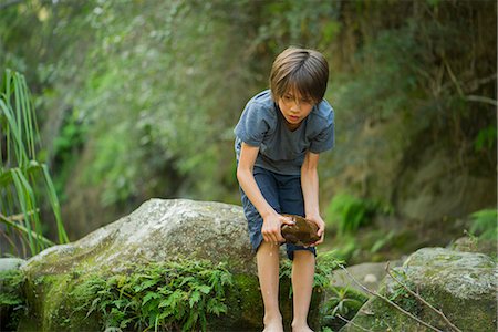 Boy bending over to pick up large wet rock Stock Photo - Premium Royalty-Free, Code: 633-08482177