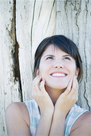 Woman leaning against tree trunk, looking up and smiling hopefully Foto de stock - Sin royalties Premium, Código: 633-08482212
