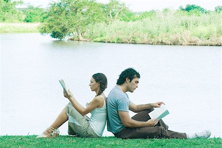 Couple sitting near edge of water, back to back, reading Stock Photo - Premium Royalty-Free, Code: 633-01574037