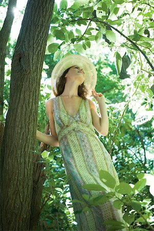 simsearch:633-01574151,k - Young woman wearing sundress and sun hat, standing next to tree, low angle view Stock Photo - Premium Royalty-Free, Code: 633-01574151