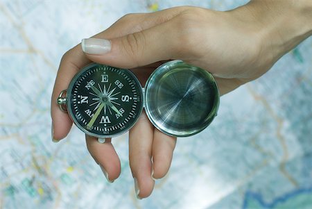 Woman's hand holding compass, map in background Stock Photo - Premium Royalty-Free, Code: 633-01574483