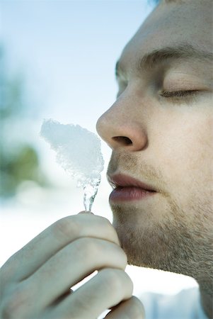 simsearch:633-01574151,k - Young man smelling piece of snow, eyes closed Stock Photo - Premium Royalty-Free, Code: 633-01574583