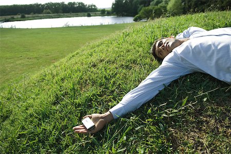 Businessman lying on grass, holding cell phone Stock Photo - Premium Royalty-Free, Code: 633-01573582