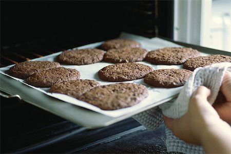 Taking sheet of cookies out of the oven Stock Photo - Premium Royalty-Free, Code: 633-01573669