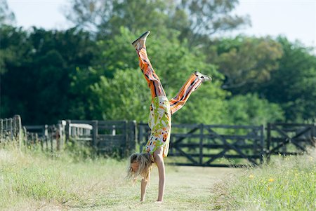 Young woman doing handstand in rural field Stock Photo - Premium Royalty-Free, Code: 633-01714102