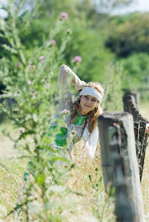 simsearch:633-01574151,k - Young woman leaning against rural fence, smiling at camera Stock Photo - Premium Royalty-Free, Code: 633-01714127