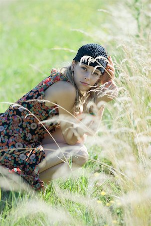 simsearch:633-01574151,k - Young woman crouching in tall grass, smiling at camera Stock Photo - Premium Royalty-Free, Code: 633-01714140